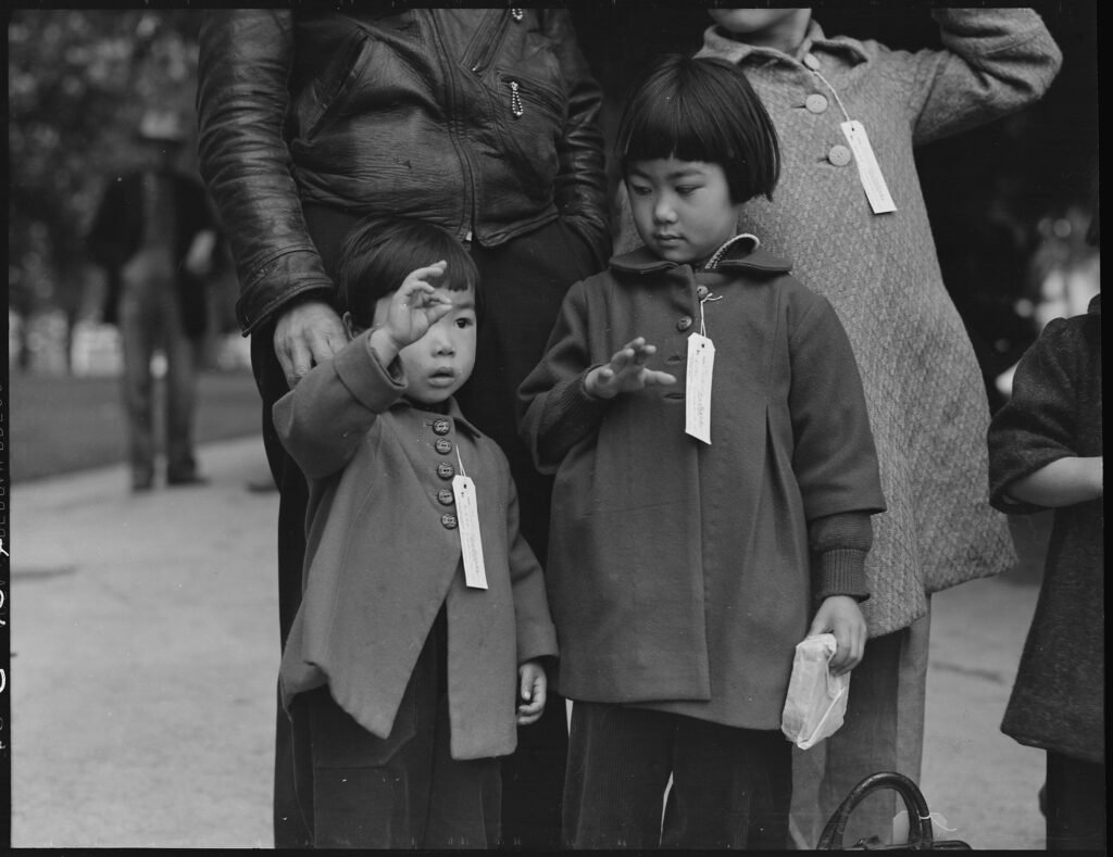 Two Children of the Mochida Family who, with Their Parents, Are Awaiting Evacuation.. Identification tags were used to aid in keeping a family unit intact during all phases of evacuation. Mochida operated a nursery and five greenhouses on a two-acre site in Eden Township. (Dorothea Lange)